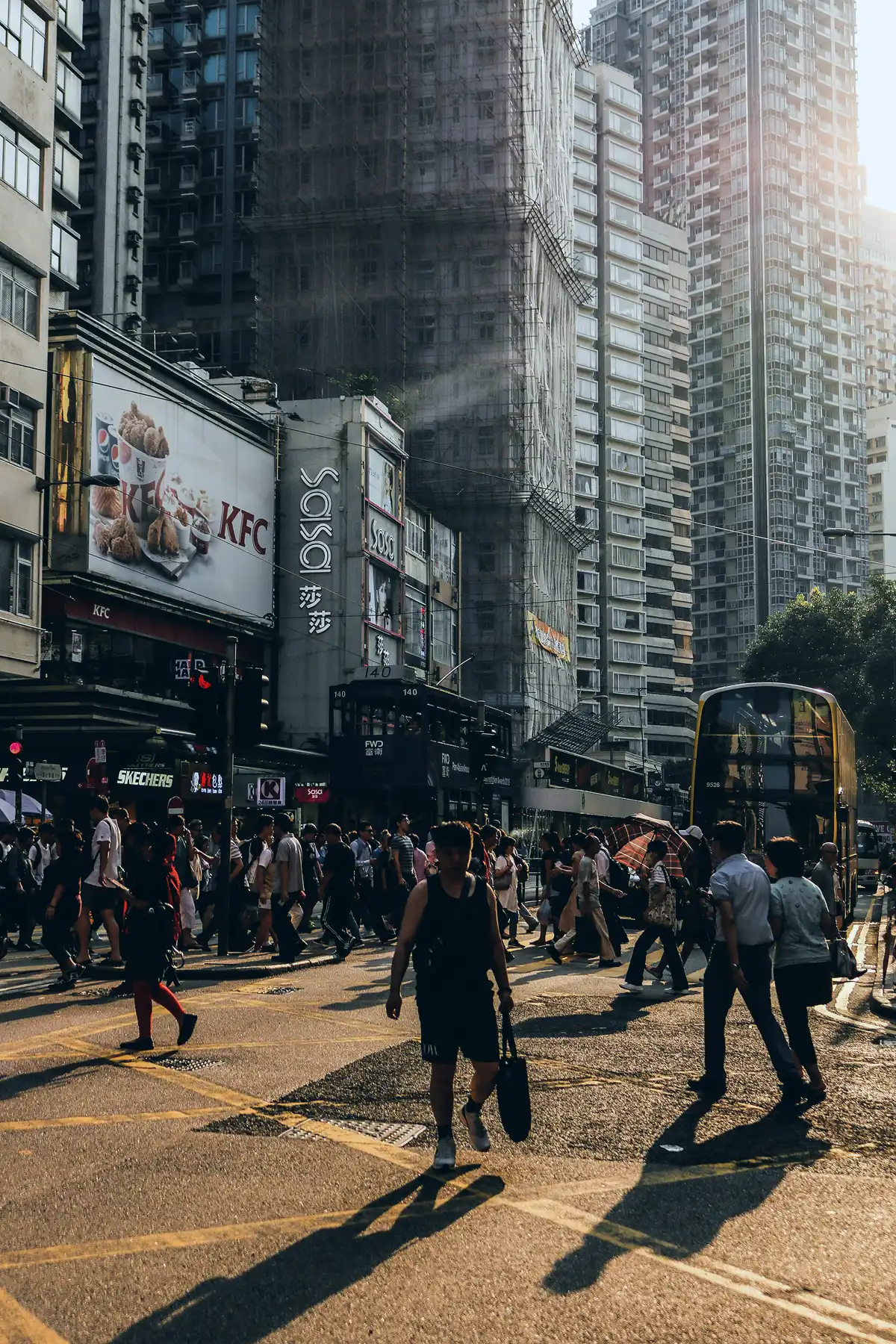 Pedestrians crossing a street on Hong Kong Island during golden hour