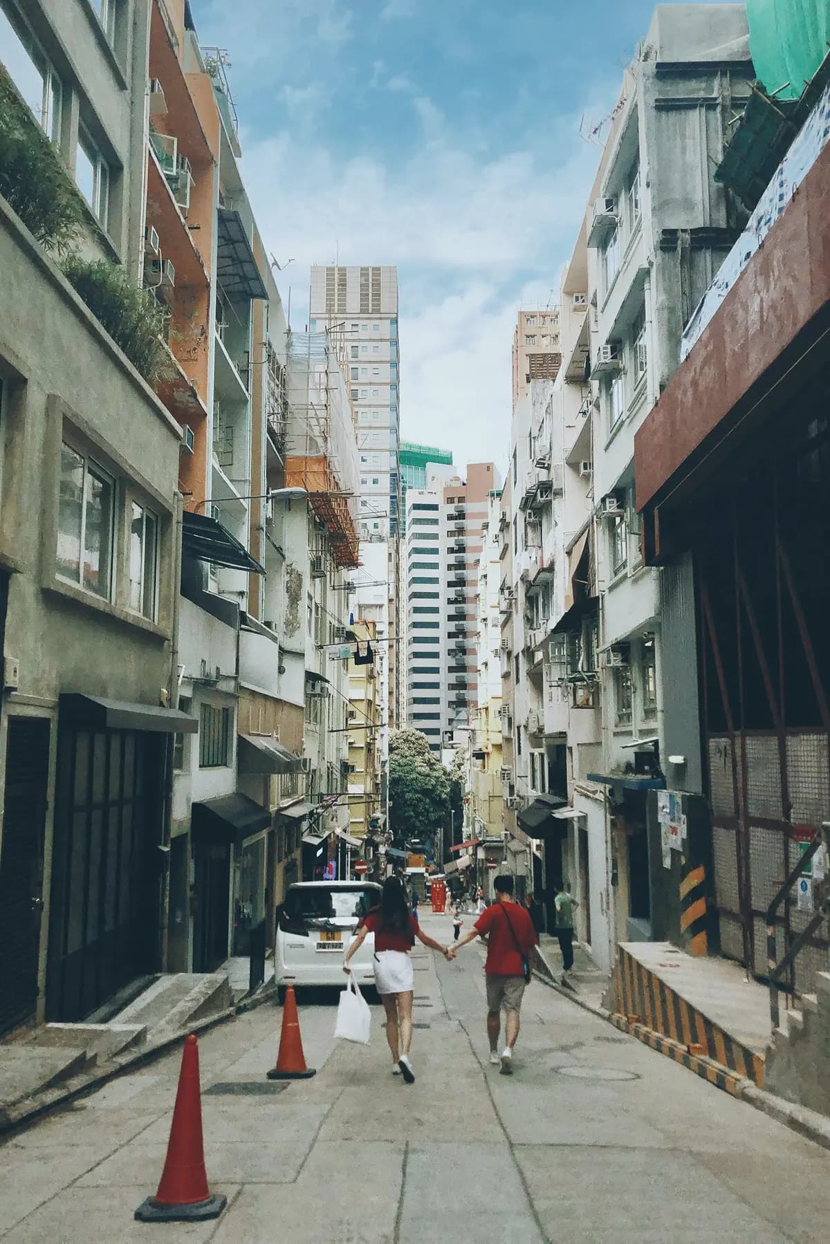 A quiet side street in Sheung Wan with people walking past cafés